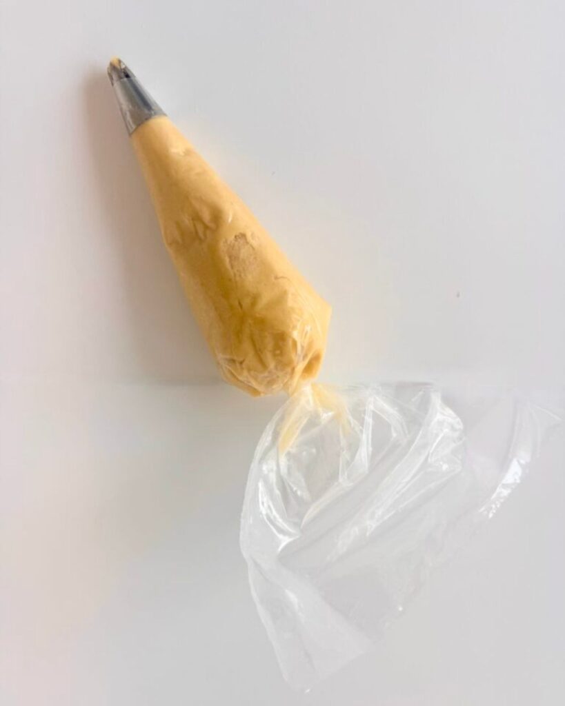 A piping bag fitted with a star tip and filled with almond shortbread cookie dough, next to an empty bag.