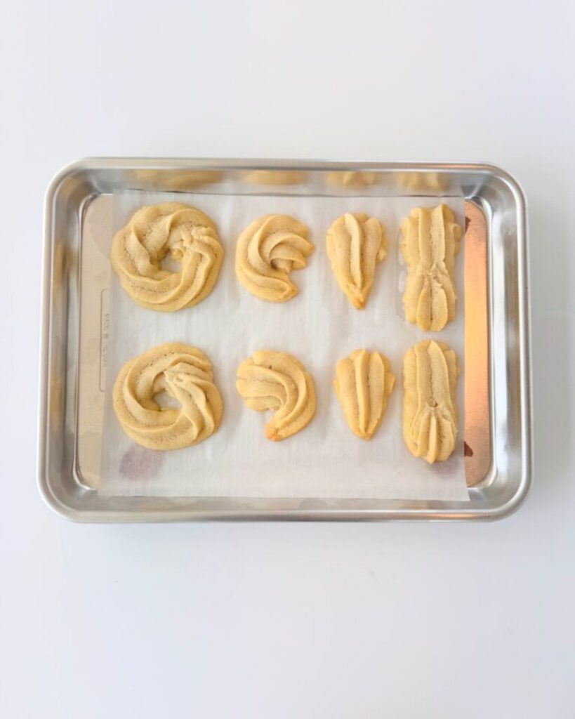 Baked almond shortbread cookies on a sheet pan, barely golden at the edges.